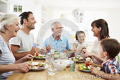 Multi Generation Family Eating Meal Around Kitchen Table Stock Photo