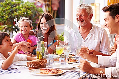 Multi Generation Family Eating Meal At Outdoor Restaurant Stock Photo
