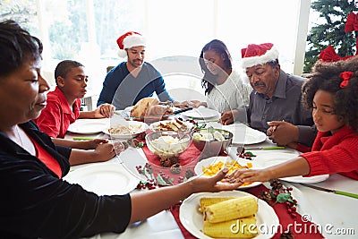 Multi Generation Family Praying Before Christmas Meal Stock Photo