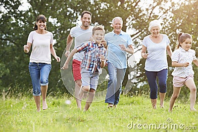 Multi Generation Family Running Across Field Together Stock Photo