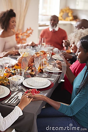 Multi generation mixed race family holding hands and saying grace before eating at their Thanksgiving dinner table, selective focu Stock Photo