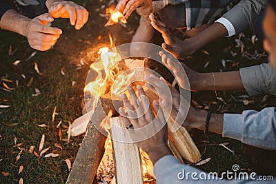 Young friends warming hands by fire at forest Stock Photo