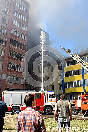 A multi-storey building is on fire and there are fire trucks nearby to extinguish the fire Editorial Stock Photo