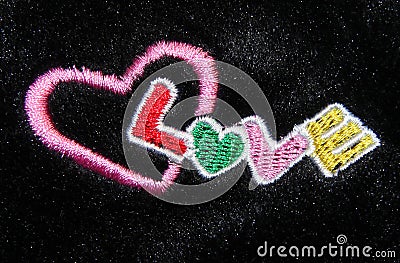 Multicolor hand embroidery word Love on black fur Stock Photo