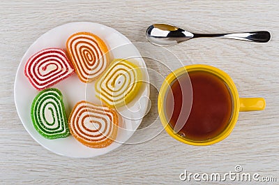 Multicolor spiral marmalades in plate, cup of tea, spoon Stock Photo