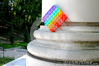 Multicolored antistress popit toy in the park near the column Stock Photo