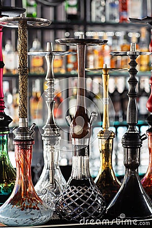 Multicolored beautiful hookahs stand on the table on the background of alcohol at the bar. Trendy hookah. active Stock Photo