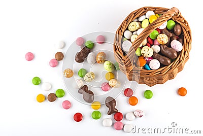 Multicolored candies and candies that look like eggs in an Easter basket with a copy of the space, top view Stock Photo