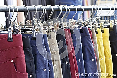 Multicolored casual pants hanging on hanger close up, side view Stock Photo