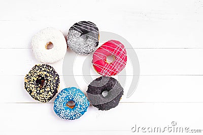 Multicolored decorated doughnuts laying on white wooden background. Sweet donuts on the table. Stock Photo