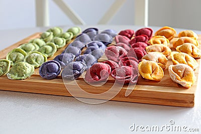 Multicolored dumplings are on a wooden board Stock Photo