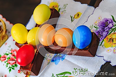 Multicolored eggs decorated for Easter holiday. Row of colorful Easter eggs on rustic wood cross and wooden table. Top view of Stock Photo