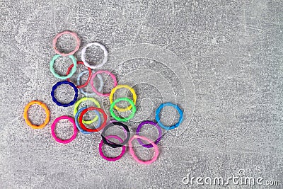 Multicolored elastic bands for hair are scattered on a gray background Stock Photo