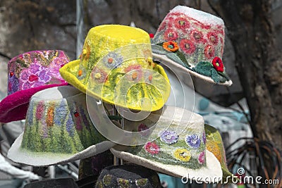 Multicolored handmade women`s hats made of felt with decorations and embroidery are sold in the shop Stock Photo