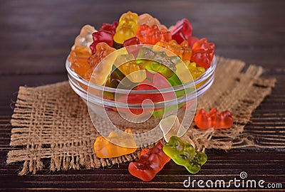 Multicolored jelly bears in a glass bowl on a dark wooden background. Editorial Stock Photo