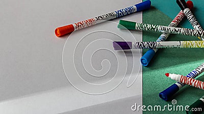 Multicolored markers lie on the background of colored cardboard and white paper close-up Stock Photo