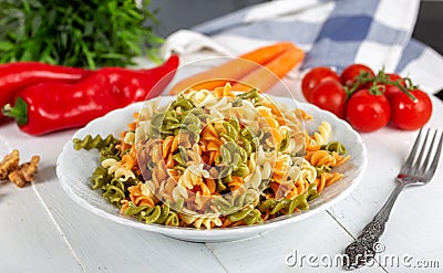 Multicolored pasta with vegetable on wooden background ve vegetables Stock Photo