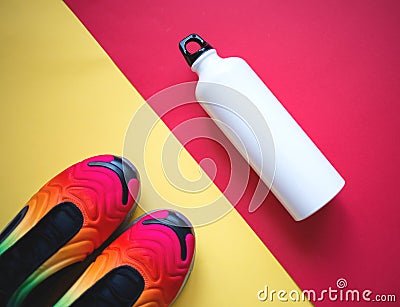 Multicolored sneakers water bottle on yellow-red background Stock Photo
