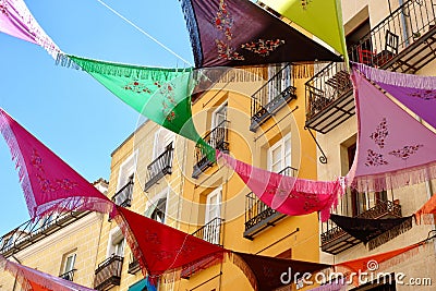 Multicolored Spanish shawls are strung between the balconies outside on the street. The decorated ambient creates a festive mood. Stock Photo