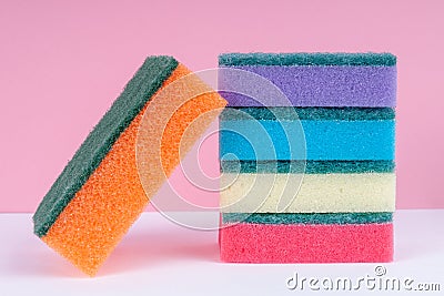 Multicolored sponges for washing dishes on top of each other on a pink background. Cleaning concept Stock Photo