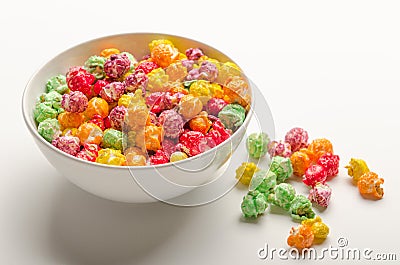 Multicolored sweet popcorn from shop in a white bowl on a white table. Delicious treat. Stock Photo
