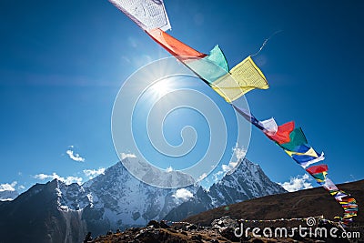 Multicolored Tibetan prayer flags with mantras flapping on the wind with High Himalayas range background. Taboche 6495m and Stock Photo