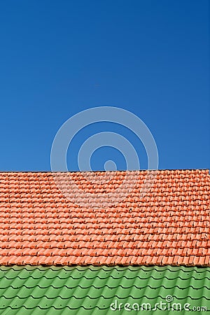 Multicolored tiled roofs of houses against the blue sky with clouds Background Attics Orange and green color Vertical Stock Photo