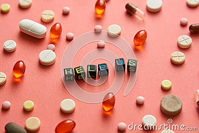 Multicolored title HELP US from black cubes on the table with tablets on coral background. Stock Photo