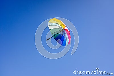 Multicolored umbrella flying suspended over bright blue sky background , with copy space Stock Photo