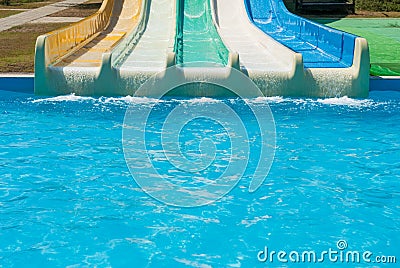 Multicolored water slides with turquoise swimming pool in amusement aqua park outdoors sunny summer vacation day with copy space Stock Photo