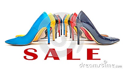 Multicolored women`s shoes with high heels standing in a row on a white surface with a red rose,Text SALE written in the middle Stock Photo