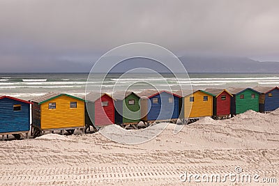 Multicoloured beach huts on beach with ocean in the background Stock Photo