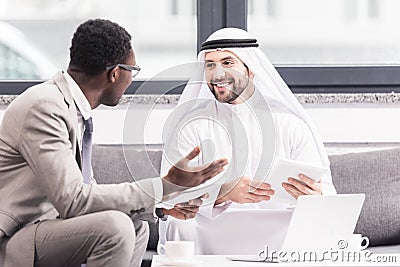 Multicultural businessmen having discussion and holding gagets Stock Photo
