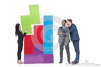 multicultural businessmen looking at asian businesswoman collecting colorful blocks Stock Photo