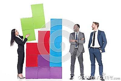 multicultural businessmen looking at asian businesswoman collecting colorful blocks Stock Photo