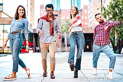 Multicultural friends walking at city center acting funny crazy moves - Happy guys and girls having fun by urban streets Stock Photo