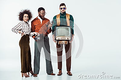 multicultural retro styled friends holding vintage television and telephone Stock Photo