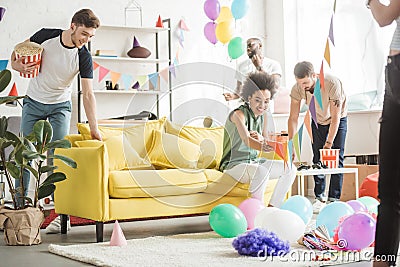 multicultural young friends decorating living room with balloons and party Stock Photo