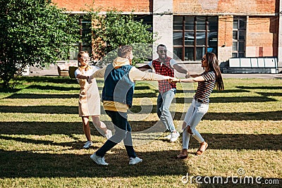 multicultural young friends holding hands while having fun together Stock Photo