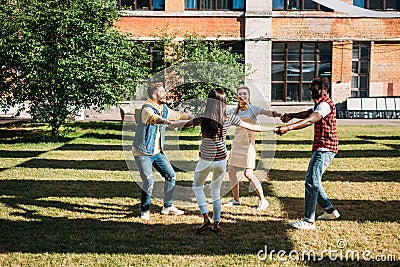 multicultural young friends holding hands while having fun together Stock Photo