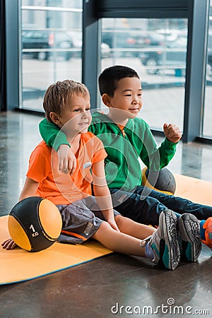 Multiethnic boys smiling, hugging and sitting Stock Photo