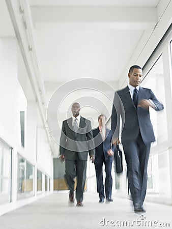 Multiethnic Businesspeople Walking In Office Corridor Stock Photo