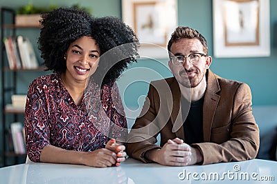 Multiethnic confident couple mature explaing something looking at camera while doing video call in the office at home Stock Photo