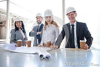 Multiethnic contractors in formal wear working with blueprints at construction area Stock Photo