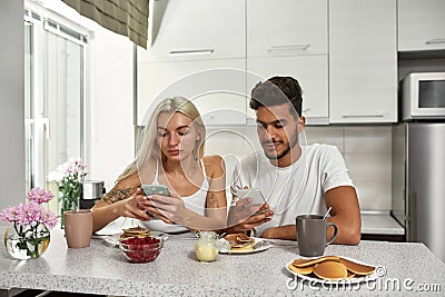 Multiethnic couple use smartphones at breakfast Stock Photo