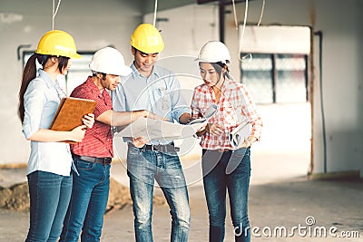 Multiethnic diverse group of engineers or business partners at construction site, working together on building`s blueprint Stock Photo