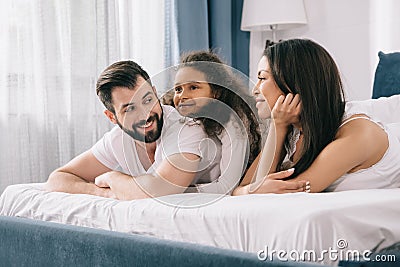 Multiethnic family with one child lying together in bed Stock Photo