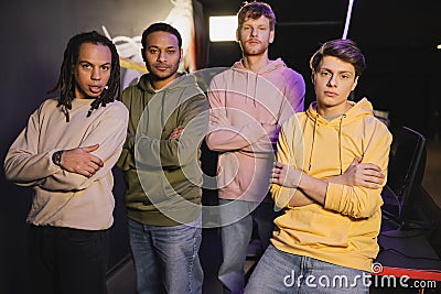 Multiethnic friends crossing arms looking at Stock Photo