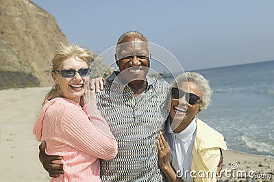 Multiethnic Friends Embracing On Beach Stock Photo