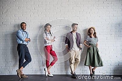 Multiethnic friends posing in stylish clothes near brick wall Stock Photo